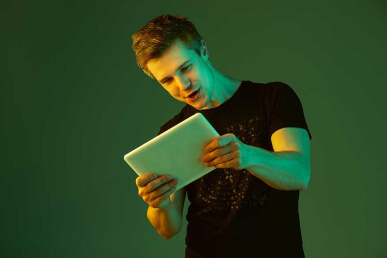 playing with tablet caucasian man s portrait isolated green studio background neon light | Techlog.gr - Χρήσιμα νέα τεχνολογίας